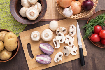 Fototapeta na wymiar Sliced mushrooms champignon with red onion on wooden cutting board on kitchen. Cooking vegetarian diet dish. Top view, flat lay