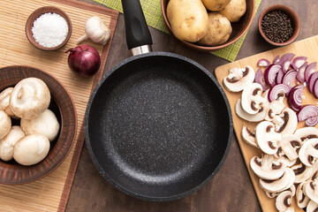 Frying pan, sliced mushrooms and vegetables on table. Top view, flatlay. Cooking healthy food concept