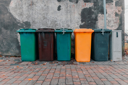 Garbage bins of different colors stand near the stone wall. Garbage separation. Eco (1138)