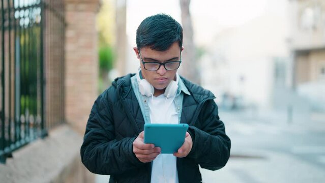 Down syndrome man wearing headphones using touchpad at street