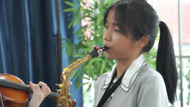 Close-up face woman teenager practicing saxophone in music school class.