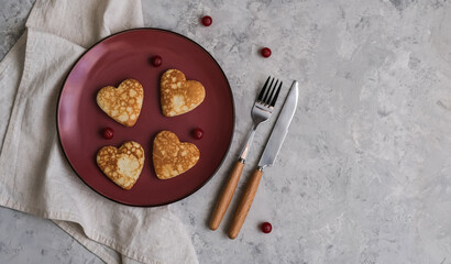 Pancakes in the shape of a heart on gray table. Breakfast for Valentine's Day. Copy space