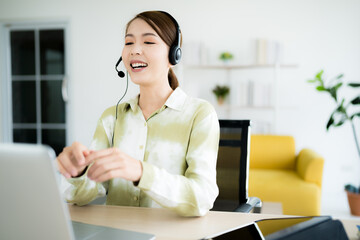 asian business woman work at home be a call center Talking to customers who call in via laptop...
