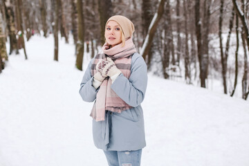 Beautiful young blond women in warm blue coat in winter park smile. Outdoor photo.