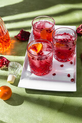 Cocktail with pomegranate juice and ice in a glass on a light green background