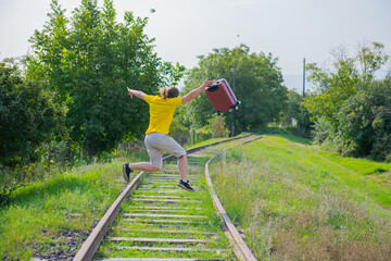 perky man with a suitcase jumping on the railroad