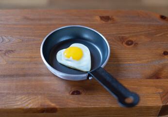 Fried eggs with a heart-shaped yolk in a frying pan. Romantic breakfast