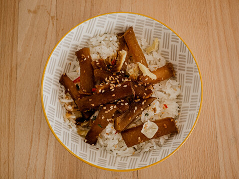 Top view of a bowl of teriyaki and rice dish on a wooden table