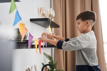 Caucasian boy decorating flat with garland from colored paper