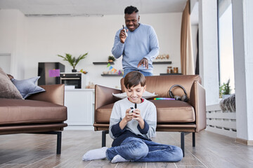 Obraz premium Man holding walkie-talkie and smiling while playing at the peekaboo with his caucasian son