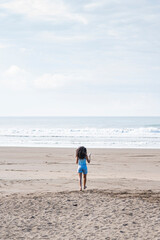Beautiful curly-haired woman running free on the sand of a beach in Costa Rica.