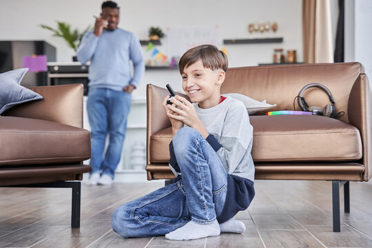 Boy sitting and talking with his father via walkie-talkie while spending time at the living room