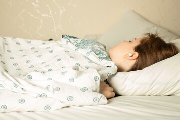 woman sleeping soundly in bed with earplugs in her ears