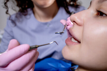 Health check. Dentist in stomatology center is making an examination of woman teeth by using dental tools