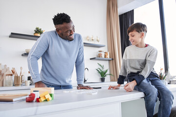 Multiracial father and his caucasian son communicating at the cozy kitchen