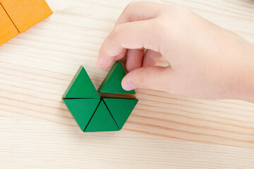 A child plays with colored blocks constructs a model on a light wooden background - 485340720