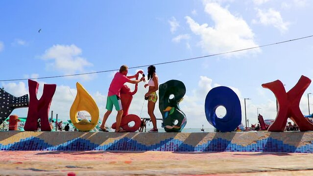 Sexy tourist couple at Holbox island colorful welcome letters Mexico.