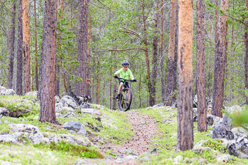 Fototapeta premium Young boy cycling with his mountainbike on forest trail