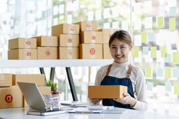 Smiling young woman preparing a package at desk