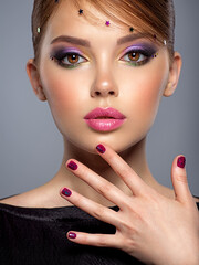 Portrait of a beautiful woman with bright makeup. Closeup female face with purple eye make-up....