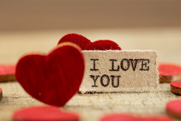 I love you - phrase typed. Valentines Day greetings concept. Little red wooden heart close up....