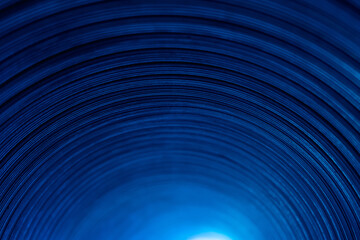 Neon tunnel. Defocused glow background. Arc shape pattern. Fluorescent illumination. Blur blue color light on dark curved grooved texture abstract overlay.