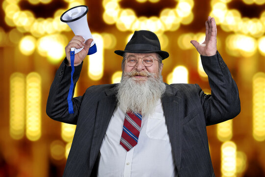 Happy senior man with megaphone standing on golden bokeh lights background.