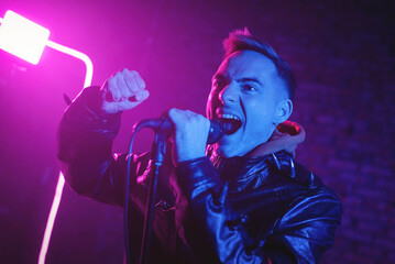 A rock singer concept. Man singing at the scene with the microphone.