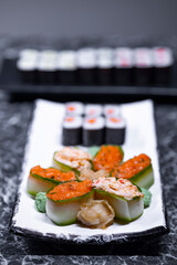 set of sushi rolls with seafood on a black stone background