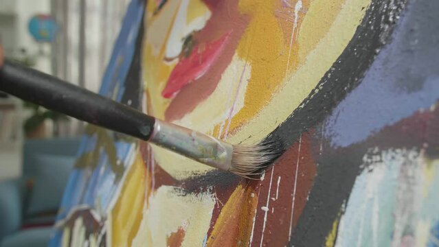 Close Up Of A Hand Holding Paintbrush Mixed Colour And Painting A Girl'S Face On The Canvas
