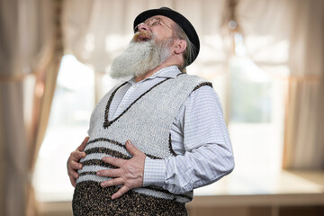 Old bearded man is lauging and touching his belly.
