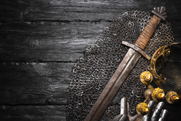 Medieval concept background with copy space. Knight sword, golden crown and armor gloves on the...