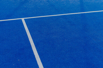 White lines of a blue paddle tennis court
