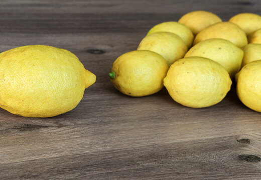 Yellow lemons fresh on brown wooden background in pyramide shape, leadership concept, one big and many small lemon fruits
