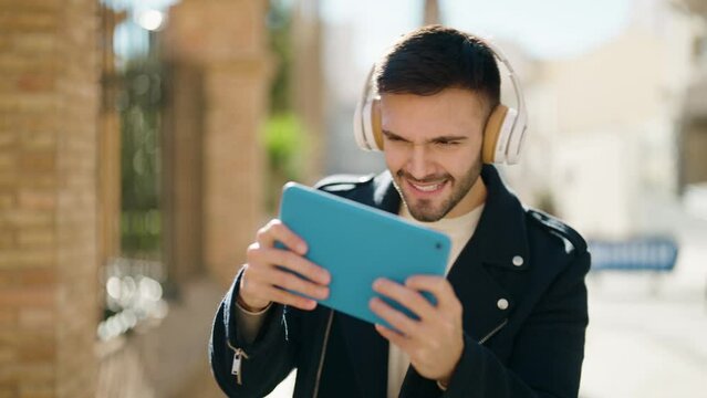 Young hispanic man smiling confident playing video game at street