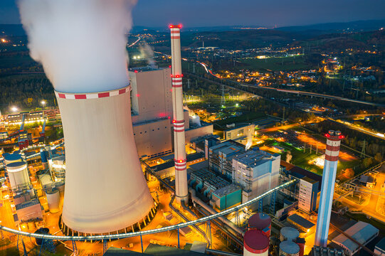 Ledvice power plant owned by CEZ. Aerial view of chimneys, cooling tower and buildings in the evening. Industrial lights from above.