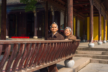 ANQING, CHINA - MARCH 22: Senior Man and Woman sit on a long bench to take a break. A  senior couple, 80 years old, sit on a bench inside Yinjiang Temple on  March 22, 2014 while they visit the temple