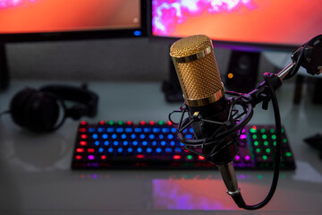 Professional microphone with gamer workstation in the background and headphones