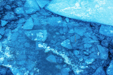 Winter nature background with blocks of ice on frozen water in spring. Abstract background of...