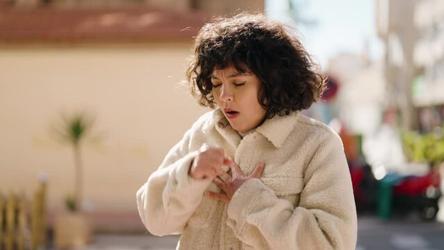 Young hispanic woman coughing at street