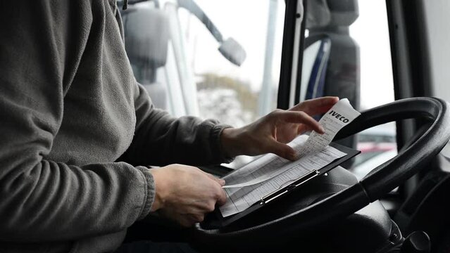 Truck driver doing his paperwork. Driver finishes his day shift in a cab.