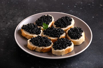 Slices of bread with black caviar on plate