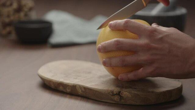 Man cut grapefruit on olive wood board