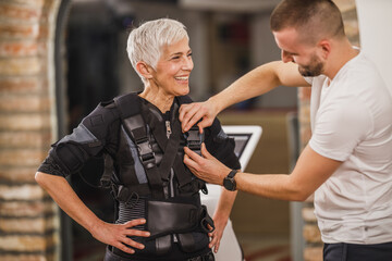 Fitness Instructor Putting An Ems Suit To A Woman