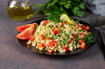 Traditional oriental salad Tabouleh with bulgur and parsley on brown background