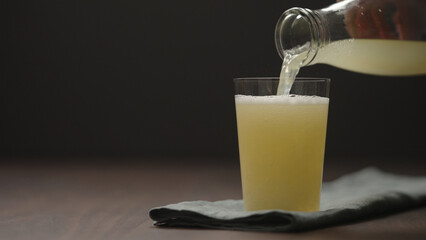 pour lemonade in tumbler glass on wood table with copy space