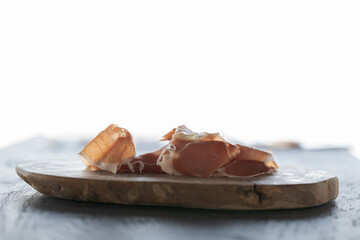 Thin slices of jamon on olive wood board