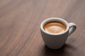 Cup of fresh espresso in white cup on walnut table with copy space