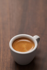 Cup of fresh espresso in white cup on walnut table with copy space