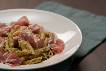 Penne pasta with capocollo, pesto and parmesan cheese